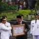 Menteri Dalam Negeri (Mendagri) Tito Karnavian saat menyerahkan anugerah tanda kehormatan Satyalancana Karya Bhakti Praja Nugrah kepada Wali Kota Medan Muhammad Bobby Nasution pada puncak peringatan Hari Otonomi Daerah (Otda) XXVI di Balai Kota Surabaya, Kamis (25/4/2024). (kedannews.com/ist).