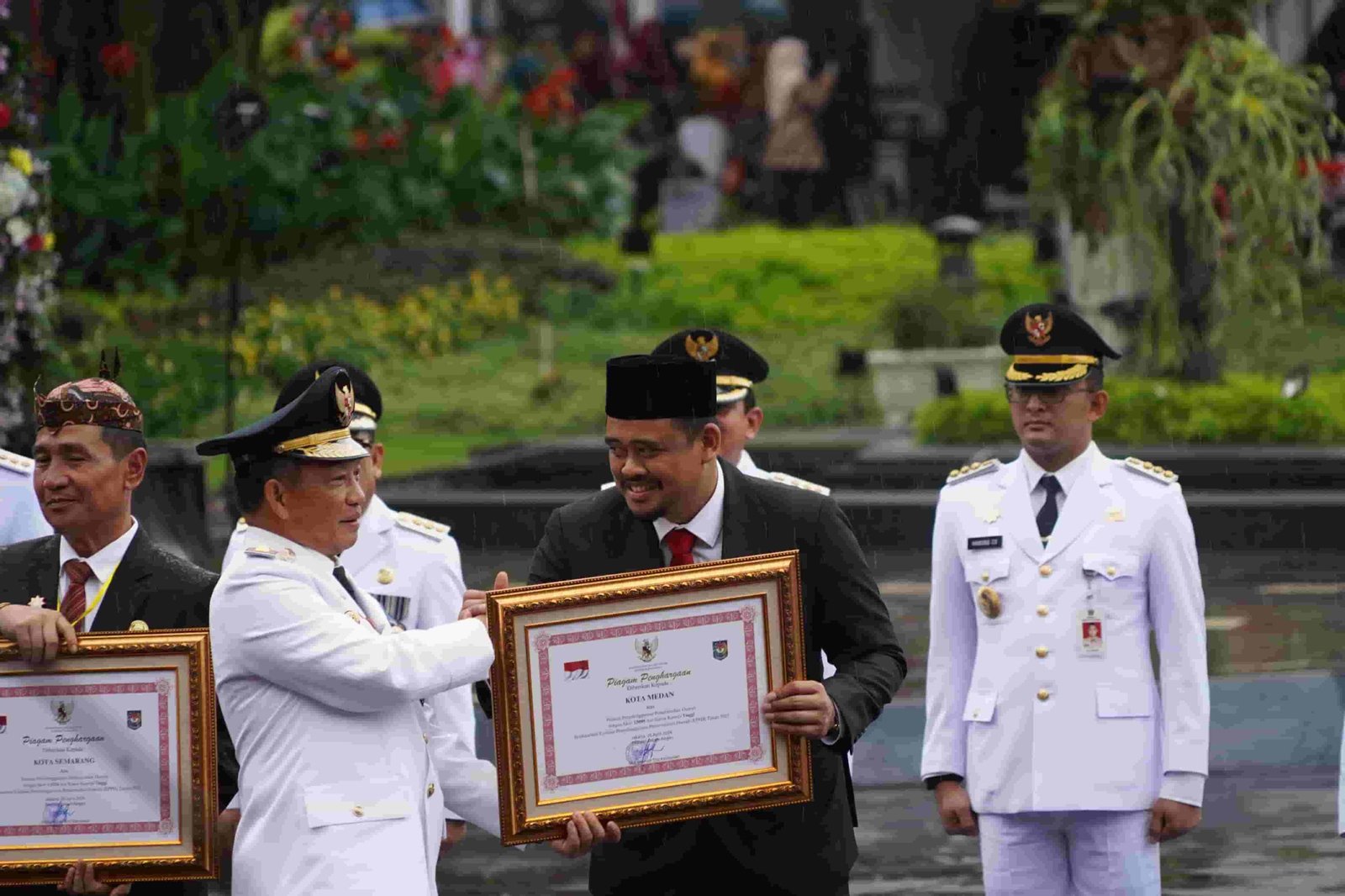 Menteri Dalam Negeri (Mendagri) Tito Karnavian saat menyerahkan anugerah tanda kehormatan Satyalancana Karya Bhakti Praja Nugrah kepada Wali Kota Medan Muhammad Bobby Nasution pada puncak peringatan Hari Otonomi Daerah (Otda) XXVI di Balai Kota Surabaya, Kamis (25/4/2024). (kedannews.com/ist).